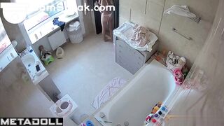 A skinny beauty gently rubs lotion on her small breasts in the bathroom
